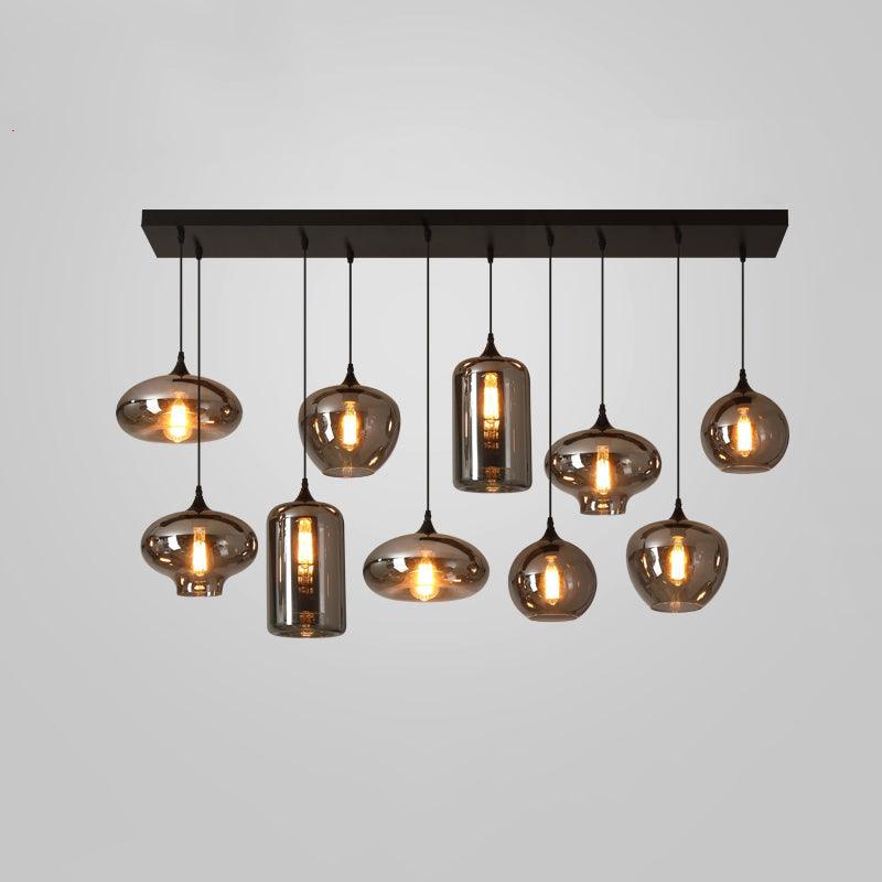 Ten smoke glass shades of varied shapes hang from the black canopy of this Clérachic pendant on a grey backdrop.