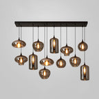 Eleven mixed shades, globes, discs and cylinders, hang from one black canopy on this Clérachic pendant, lit warm.