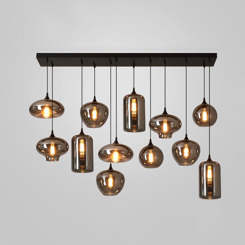 Eleven mixed shades, globes, discs and cylinders, hang from one black canopy on this Clérachic pendant, lit warm.