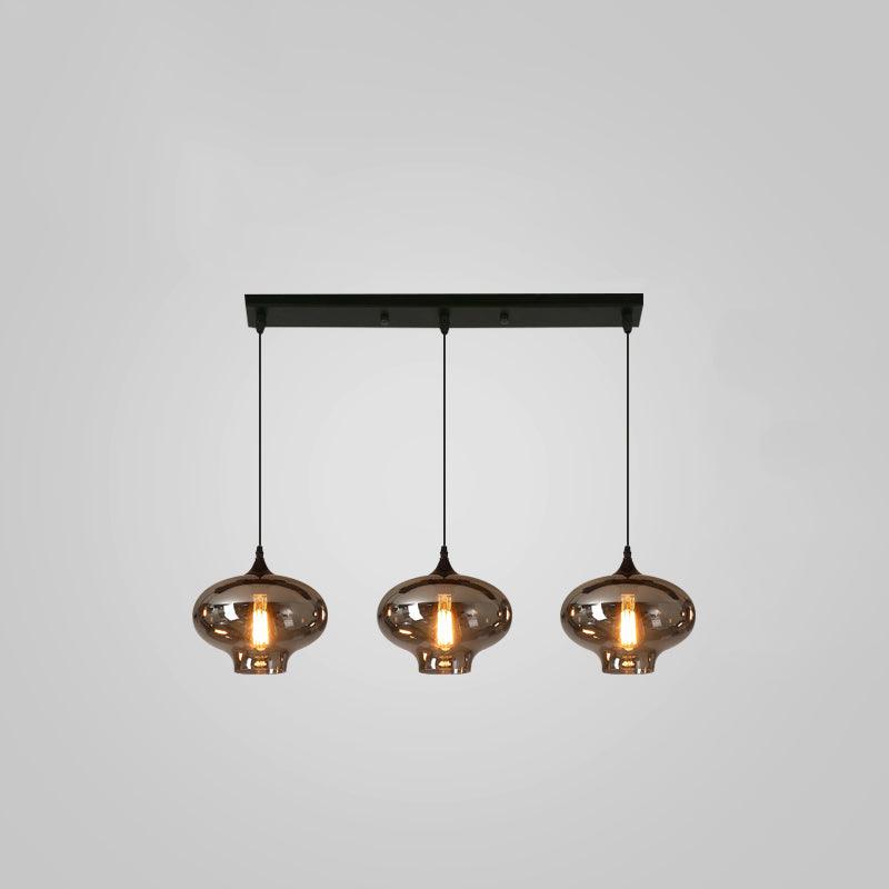 Three smoke glass shades with a narrow neck hang evenly from a black bar canopy on this Clérachic pendant.