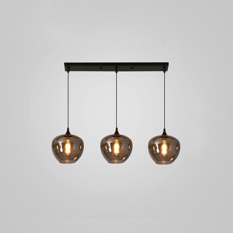 Three rounded smoke glass shades hang from a slim black canopy on this Clérachic pendant, glowing warm on grey.