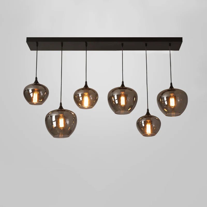 Six smoke glass globes in staggered drops hang under a long black canopy on this Clérachic pendant, lit on grey.