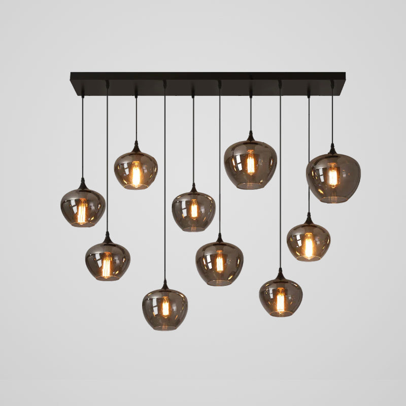 Ten rounded smoke glass shades on this Clérachic pendant hang at uneven heights beneath a long black canopy.