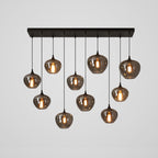 Ten rounded smoke glass shades on this Clérachic pendant hang at uneven heights beneath a long black canopy.
