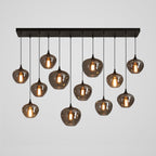 Twelve smoke glass globes of this Clérachic pendant hang from a long black canopy, arranged in a loose staggered pattern.