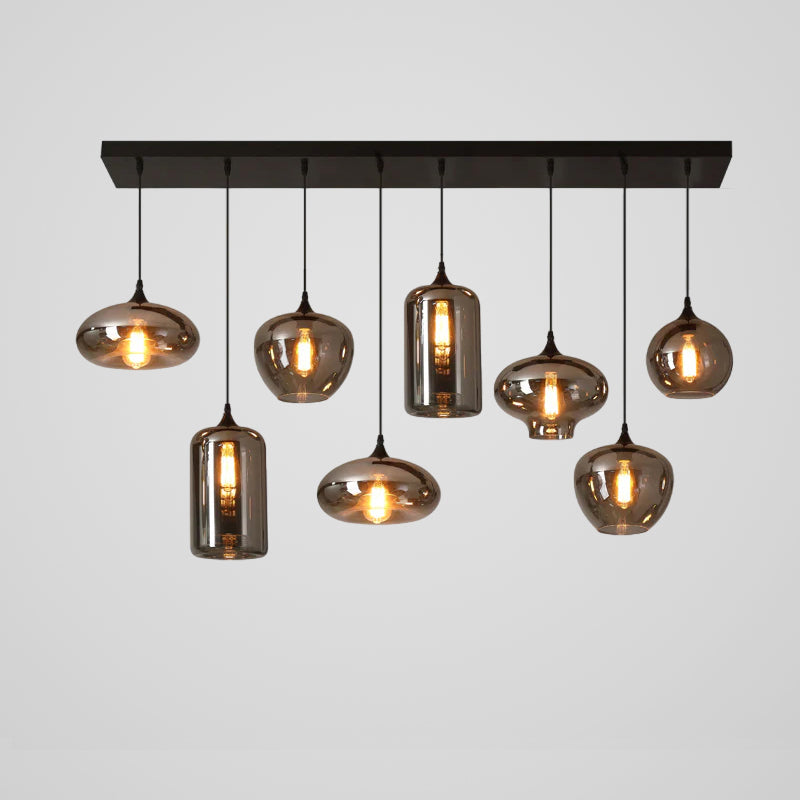 Eight mixed smoke glass shapes hang from a black canopy on this Clérachic pendant, with two tall cylinders among them.