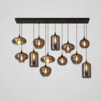 Twelve mixed smoke glass shades hang from a long black canopy on this Clérachic pendant, with cylinders among the globes.