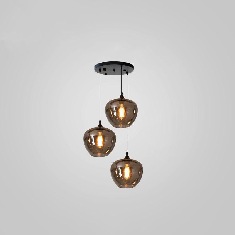 Three rounded smoke glass shades hang from a round black ceiling plate on this Clérachic pendant, lit on a grey backdrop.