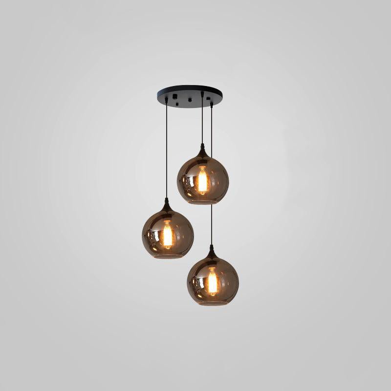 Three round smoke glass globes hang at staggered heights from a round black canopy on this Clérachic pendant.