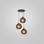 Three round smoke glass globes hang at staggered heights from a round black canopy on this Clérachic pendant.