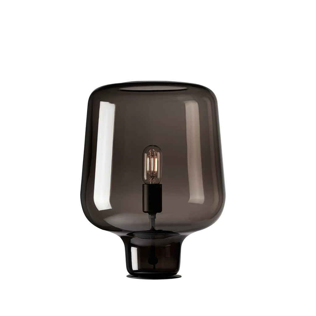 This Clérachic smoke grey glass table lamp on a white background, with a bulb in a black holder and a thin black foot.