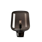 This Clérachic smoke grey glass table lamp on a white background, with a bulb in a black holder and a thin black foot.