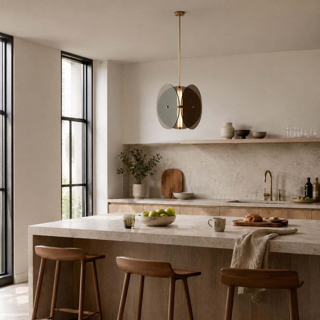 Clérachic disc pendant with smoke-grey glass hanging in a pale kitchen above a stone island with three wooden stools.