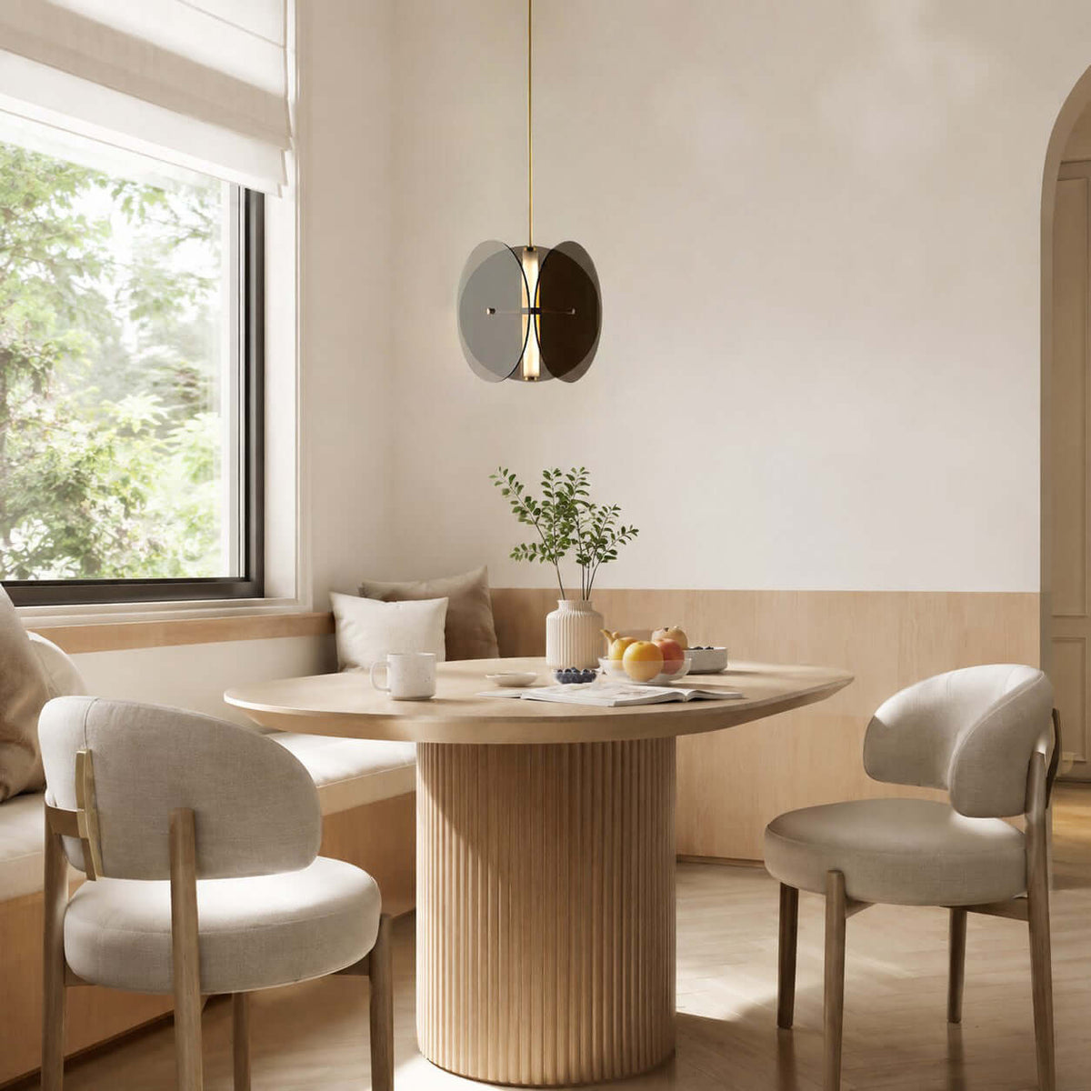 Smoked glass pendant light from Clérachic above a round dining table in a breakfast nook with cream upholstered chairs.