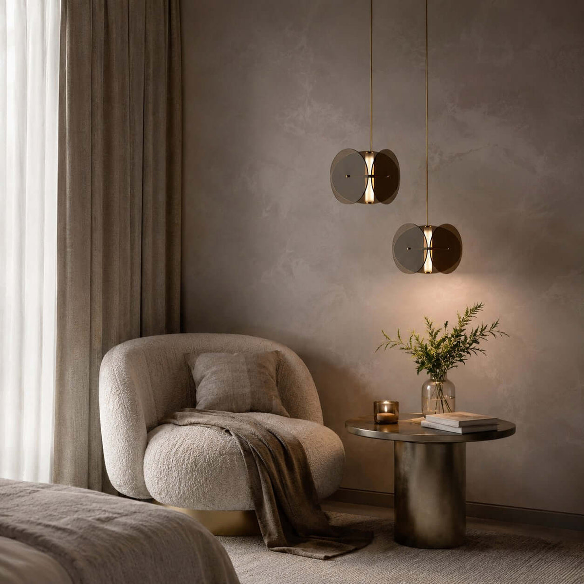 Pair of smoked glass pendants from Clérachic at different heights, above a boucle armchair and a brass side table.