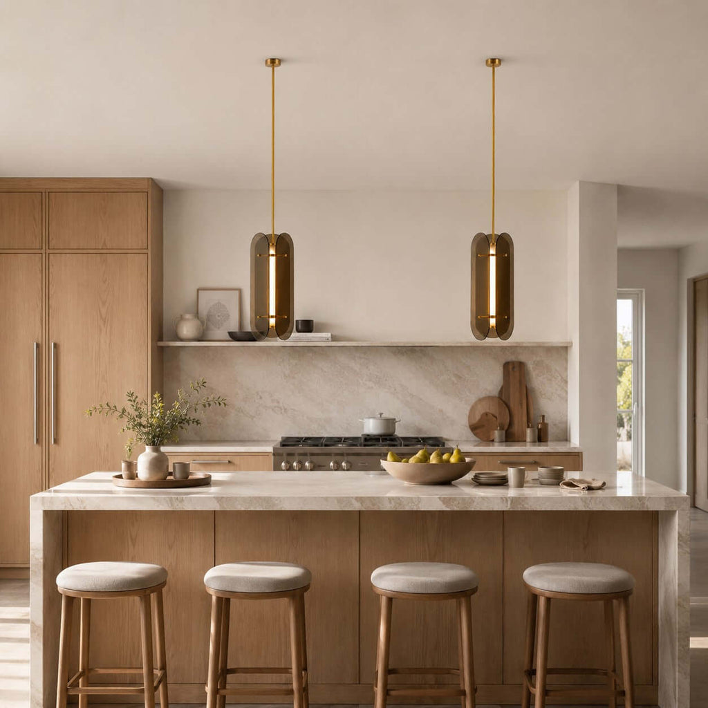Clérachic glass pendants with brass rods hanging over a marble-topped kitchen island with four round-seated stools.
