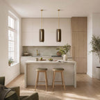 Pair of slim Clérachic pendants in a bright kitchen with oak cabinets, a stone island and two green-topped stools.
