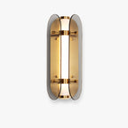 Clérachic wall light with two curved smoked-grey glass wings around a lit, frosted tube and brass bands, on a plain white backdrop.
