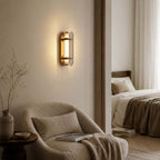 Lit Clérachic smoked-glass wall light on a taupe wall, beside a boucle armchair and a doorway into a bedroom.