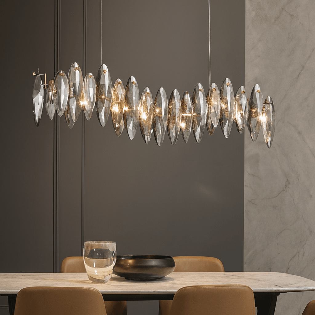 Clérachic long wave chandelier of smoked crystal leaves above a marble dining table with tan leather chairs and a dark bowl.