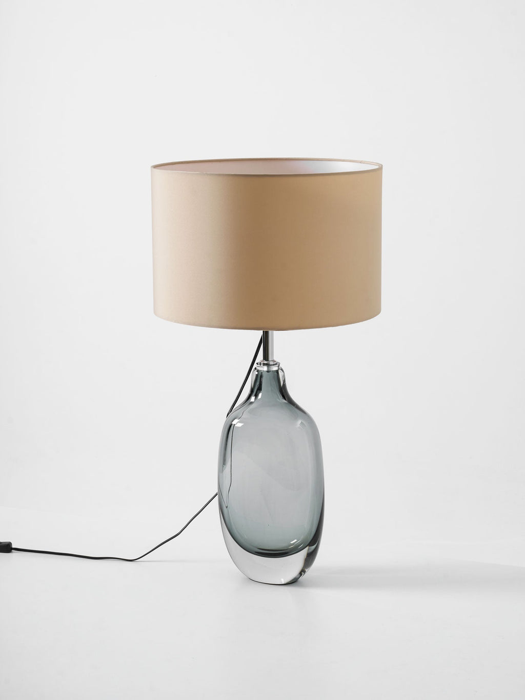 A Clérachic table lamp seen from slightly above, with the inside of its cream drum shade and the cord trailing across a white surface.
