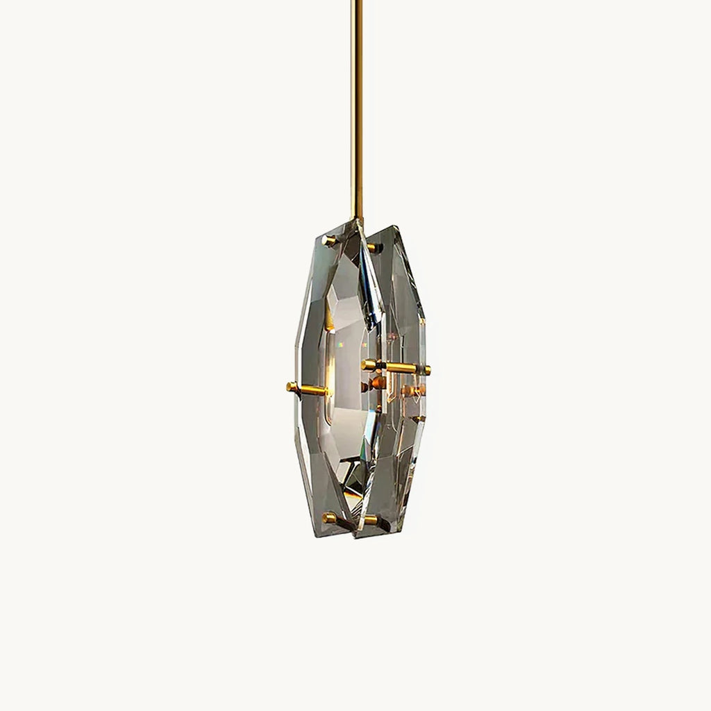 A faceted smoky grey crystal pendant from Clérachic on a brass rod, with brass pins holding two cut panels around a filament bulb, on white.