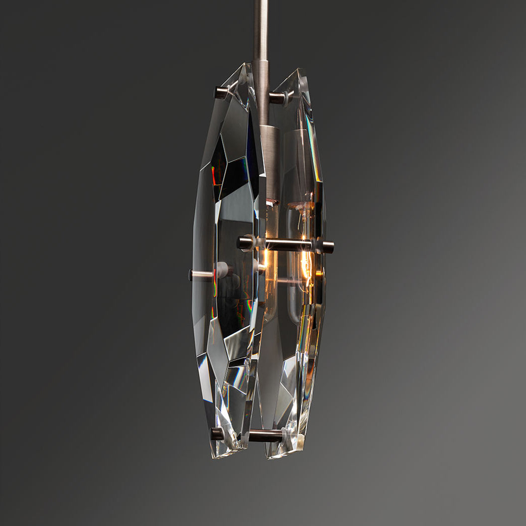 Side view of this Clérachic pendant, showing the two thick cut crystal panels held apart by brass pins around a glowing bulb.