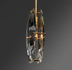Angled view of the Clérachic pendant with the brass stem, a lit filament bulb and two faceted crystal panels on a dark grey backdrop.