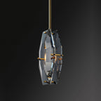 Smoky crystal Clérachic pendant seen at a slight turn on a near-black background, with brass pins at the edges of the panels.