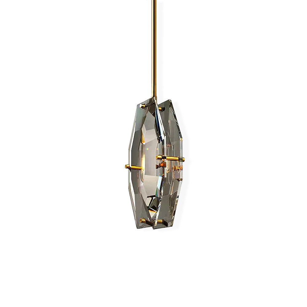 Clérachic faceted crystal pendant on a brass rod, set off-centre on a plain white backdrop with its brass pins visible.