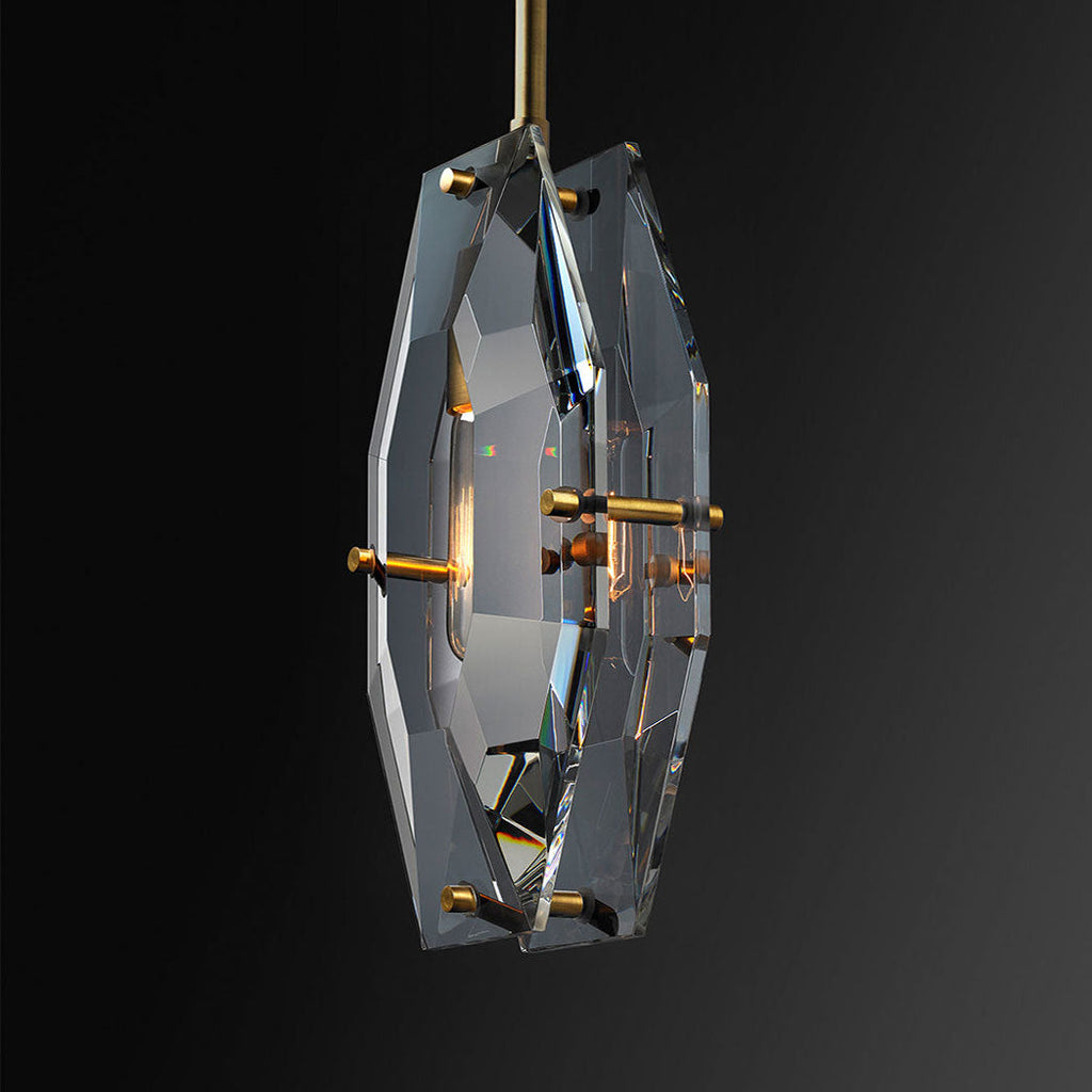 Close view of this Clérachic crystal pendant on black, with the polished cut edges, brass pins and a filament bulb inside the panels.