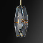 Close view of this Clérachic crystal pendant on black, with the polished cut edges, brass pins and a filament bulb inside the panels.