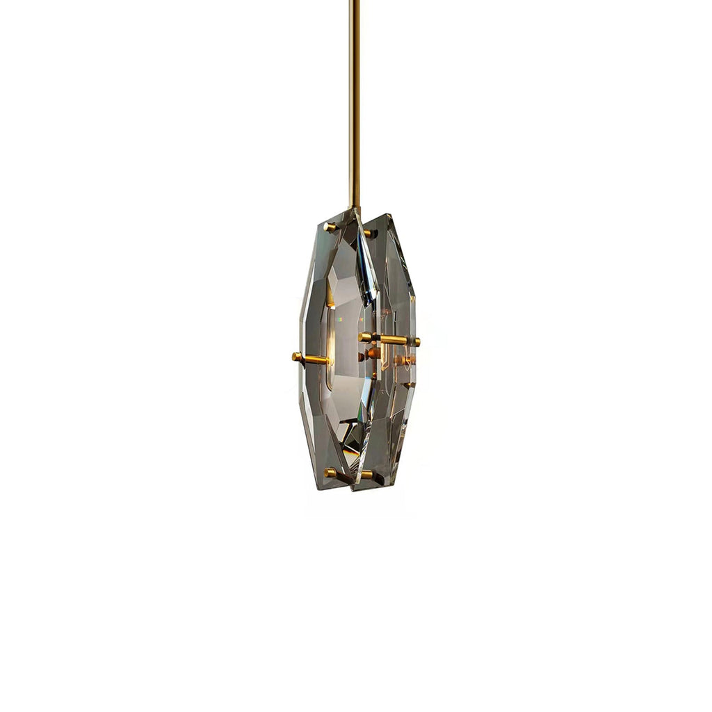 Smaller view of the Clérachic crystal pendant on white, its two brass-pinned panels and a faint bulb glow seen at an angle.