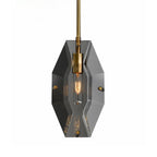 Front view of the smoky grey panel on this Clérachic pendant, with a brass bulb holder and a lit filament bulb, on a pale backdrop.