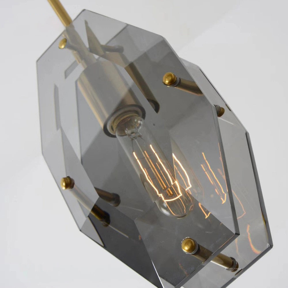 Looking up at the filament bulb inside this Clérachic pendant, with smoky grey panels, brass pins and the brass rod at an angle.