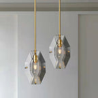 Two Clérachic crystal pendants at different heights against a pale wall and panelled door, each with a brass holder and filament bulb.