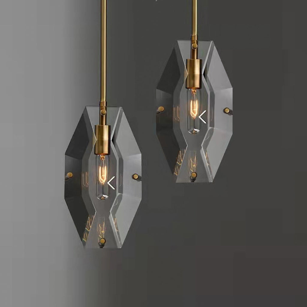 Two Clérachic crystal pendants hanging at different heights against a dark grey wall, each with a brass bulb holder.
