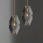 Two Clérachic crystal pendants hanging at different heights against a dark grey wall, each with a brass bulb holder.