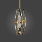 Clérachic crystal pendant on a brass rod, turned slightly to show the thick cut edge of the panels, on a grey studio backdrop.