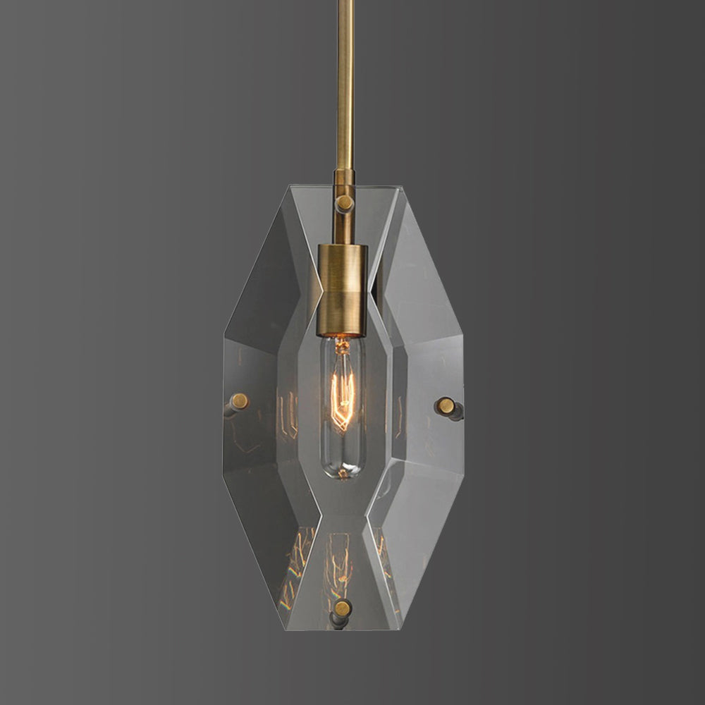 Front view of this Clérachic pendant on a mid-grey backdrop, with a hexagonal crystal panel and a brass holder around a lit bulb.