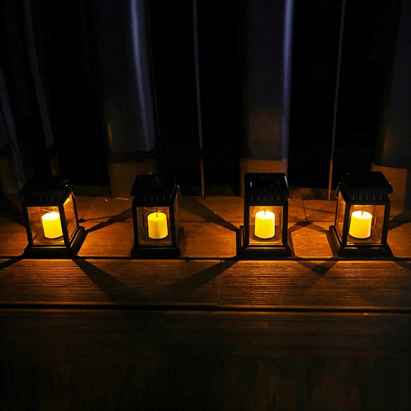 Four Clérachic black solar lanterns in a row on a wooden deck at night, each with a warm candle-style glow.