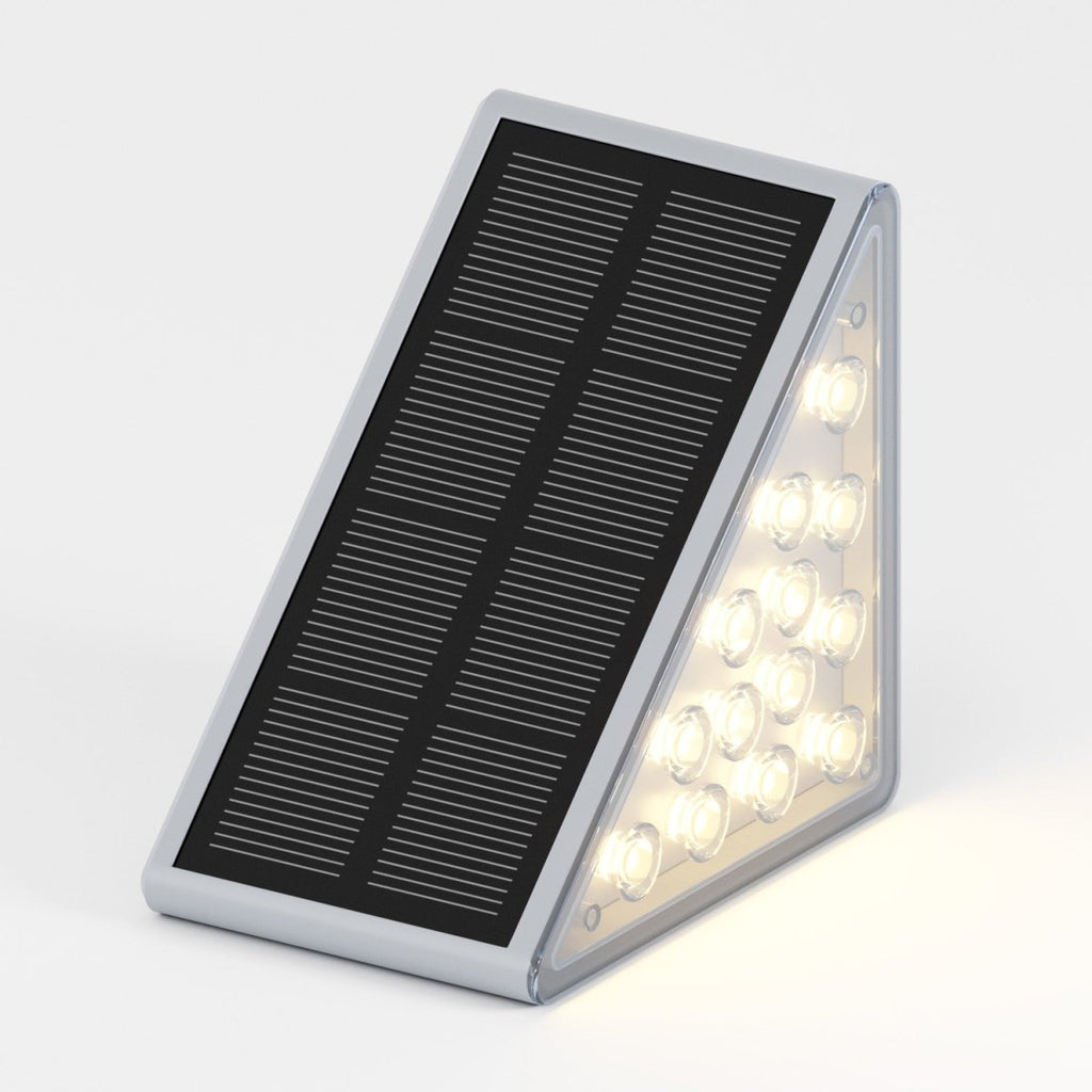 Clérachic grey solar step light glowing warmly, sixteen LEDs lit along its triangular edge on a plain background.