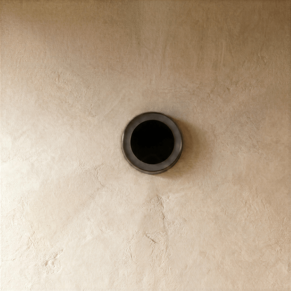 Clérachic small round solar light switched off on plaster, showing its dark solar panel in a slim steel ring.