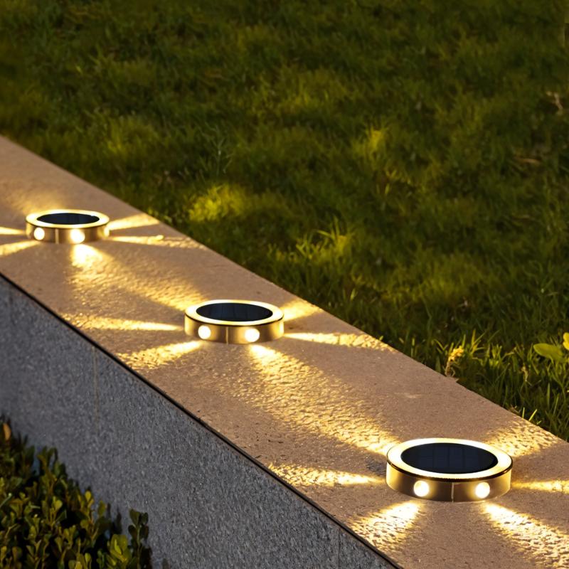 Clérachic round solar lights set along a stone garden wall coping at night, each casting warm light rays outwards.