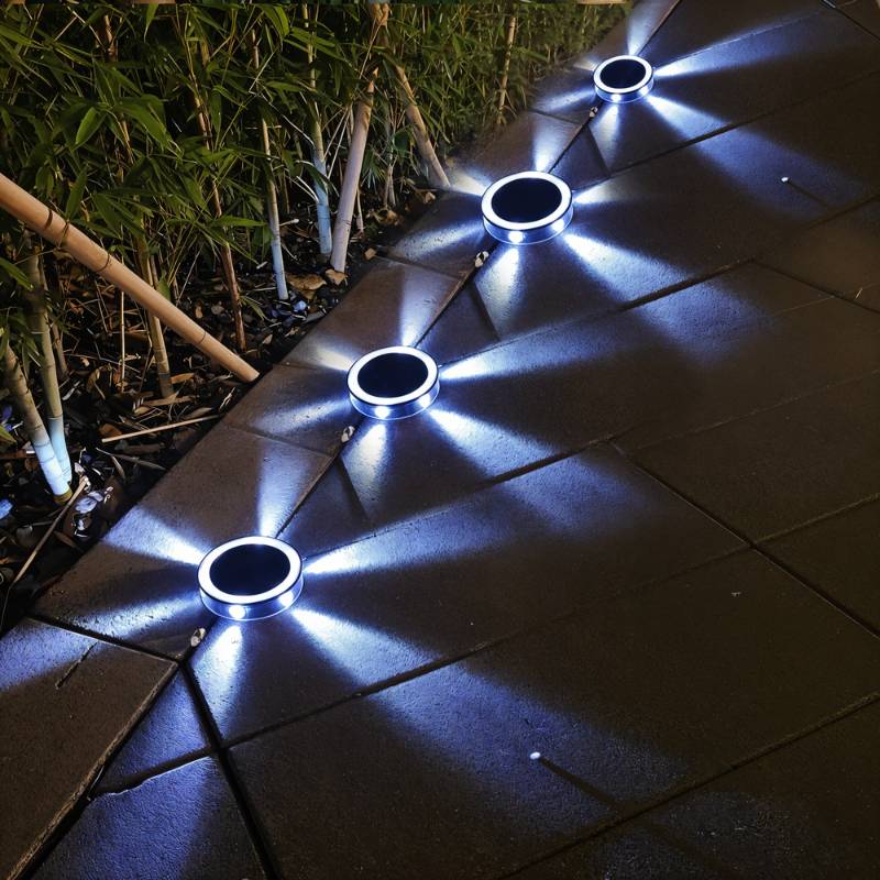 Clérachic round solar lights along a paved garden path at night, casting cool white star-shaped rays over the slabs.