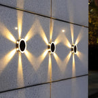 Clérachic round solar lights on a speckled stone wall at dusk, each throwing warm beams in a zigzag pattern.