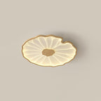 Clérachic ceiling light in a light wood-grain finish, glowing warm against a soft beige ceiling.