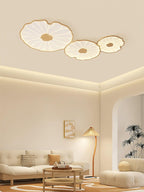 The Clérachic three-shade light in light wood-grain finish above a cream room with a rattan floor lamp.
