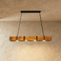 Clérachic rustic timber bar pendant with black iron straps, four warm bulbs along its underside, hung on two black chains.