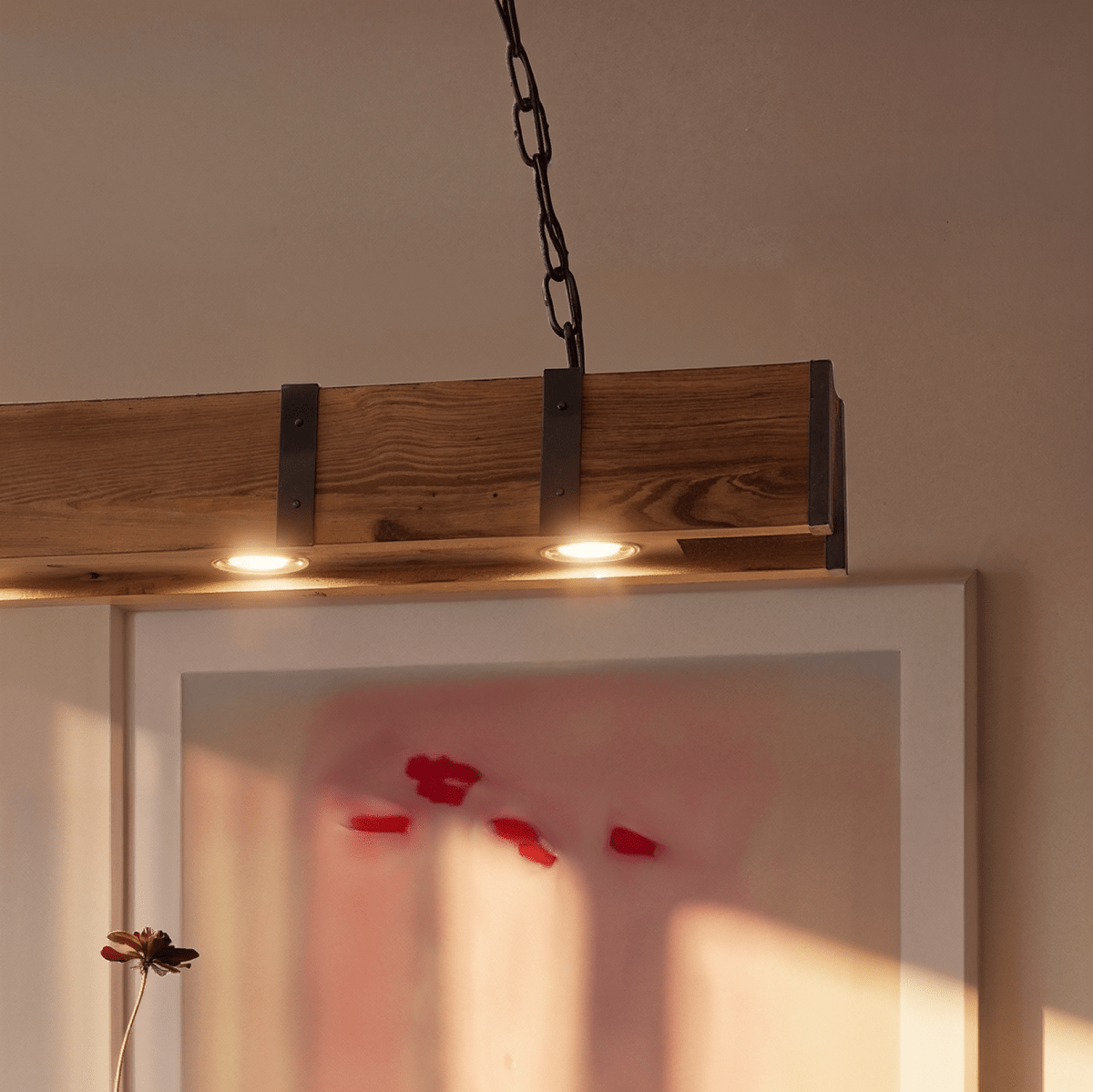 Clérachic close-up of the weathered timber beam with black iron straps and two warm bulbs set into its underside.
